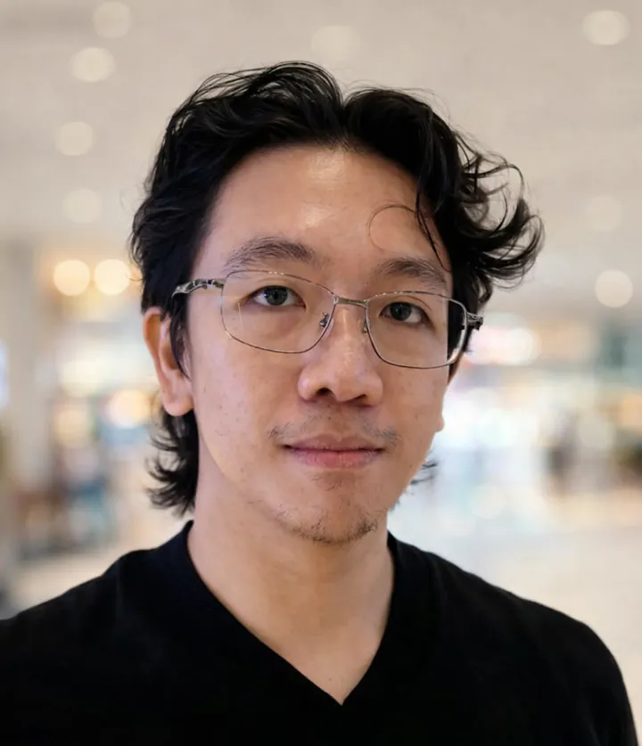 Rodruey Simbul, in glasses and a black shirt, smiling slightly.